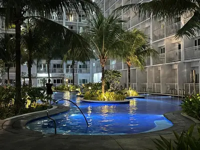 a person standing in front of a building with a swimming pool at D'Shore to Relax Shore Residences MOA PASAY in Manila