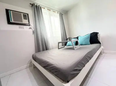 a bedroom with a bed with a air conditioner at KL Tower Studio Near Greenbelt Makati in Manila