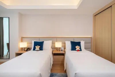 two beds in a hotel room with two lamps at Somerset Valero Makati in Manila