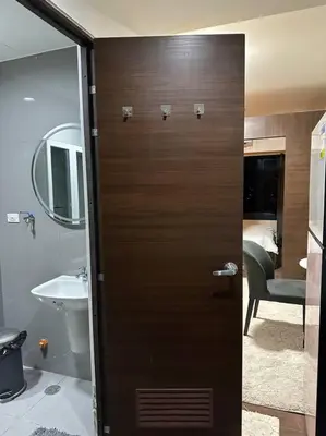 a bathroom with a wooden door with a sink at My Hideaway@Air in Manila