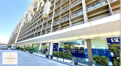 a large building on a street with benches in front of it at New York Suite - by GUEST RESERVATION'S MANILA in Manila