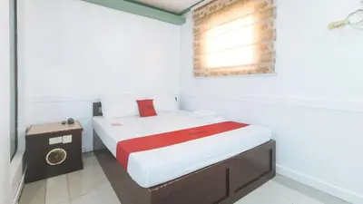 a small white room with a bed and a table at RedDoorz @ Moss Hotel Dasmarinas in Cavite