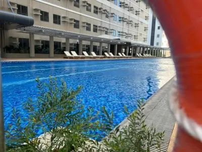 a large swimming pool with chairs in a building at SMDC Green 2 Staycation, The Traditional & Modern Fusion Condo in Pasong Bayog