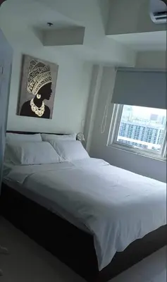a bedroom with a large white bed with a window at Cookies Nest at 100West Makati in Manila
