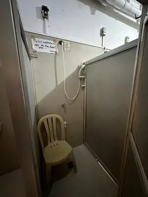 a chair in a small room with a shower at St John's Pearl Transient House in Manila