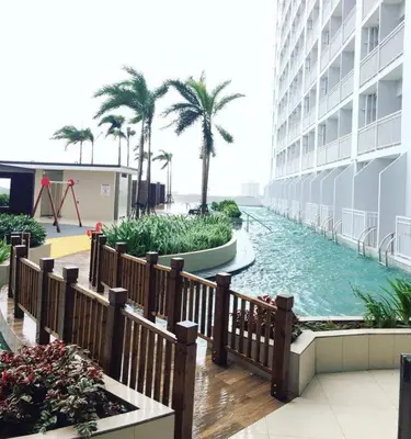 a pool in the middle of a building with palm trees at Condo Near MOA, NAIA, PICC, & CCP that is comfy with a view! in Manila