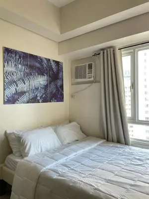 a bedroom with a bed and a window with a air conditioner at Mountain View at Beacon Tower in Manila