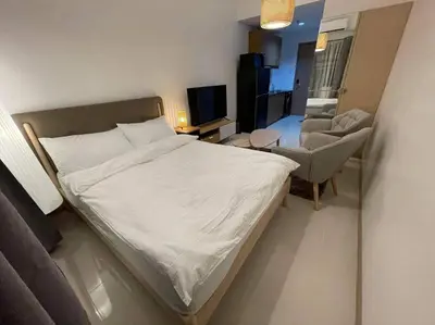 a small bedroom with a bed and a chair at House KubU at Lush Residences Makati in Manila