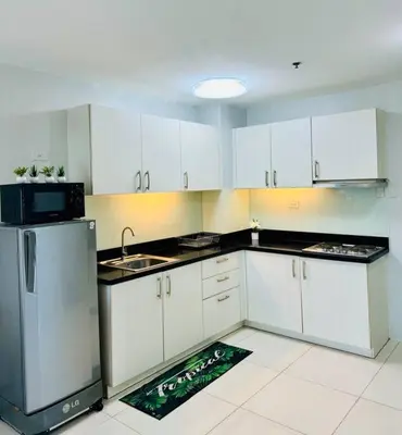 a kitchen with white cabinets and a sink and a refrigerator at Cozy Minimalist 2BR Condo at Princeton QC near Rob Magnolia in Manila