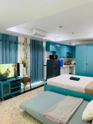 a bedroom with two beds and a kitchen with blue cabinets at Baywatch Tower in Manila