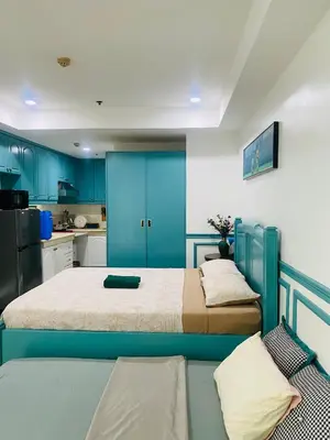 two beds in a room with blue cabinets and a kitchen at Baywatch Tower in Manila