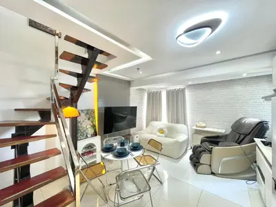 a living room with a staircase and a couch and chairs at Thompson Suites Fort Victoria Tower BGC Loft Type 1BR in Manila