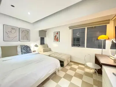 a bedroom with a bed and a couch and a window at Thompson Suites Fort Victoria Tower BGC Loft Type 1BR in Manila