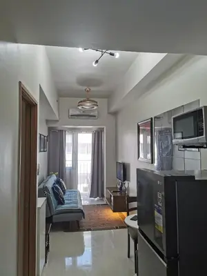 a kitchen and living room with a couch and a tv at Mall of Asia condotel in Manila
