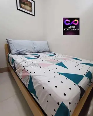 a bed with a comforter on it in a bedroom at Mall of Asia condotel in Manila