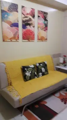 a yellow couch in a living room with paintings on the wall at Sea Residences Holiday Rentals in Manila