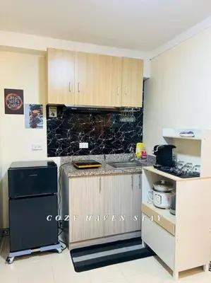 a kitchen with wooden cabinets and a black refrigerator at #46 Urban Deca Homes Ortigas in Manila