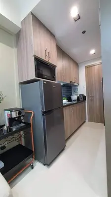 a kitchen with a stainless steel refrigerator and wooden cabinets at Luxury Condo with a view of Manila Bay in Manila