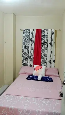 a pink bed in a room with curtains at Dencios Transient in Cabuyao