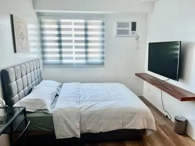 a bedroom with a bed and a flat screen tv at Modern 2BR in Central Makati! Netflix Wi-Fi Pool in Manila