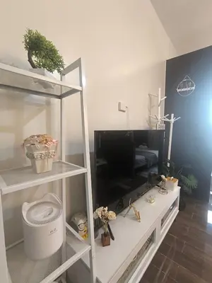 a living room with a white shelf and a tv at Sun and Moon D'wood air residences makati in Manila