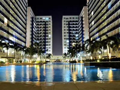 a large pool in a city at night with tall buildings at SEA 2-BR Unit with Free Parking near Mall of Asia in Manila
