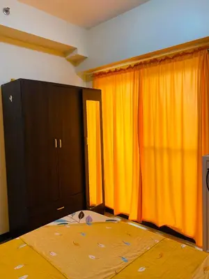 a bedroom with a bed and orange curtains at Hello condo in Manila