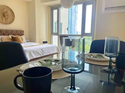 a room with a table with two glasses and a bed at Jane in the City! In Avant, BGC in Manila