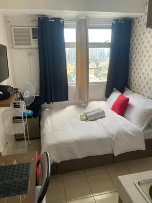 a bedroom with a bed with blue curtains and a window at Pierrecondotel in Manila