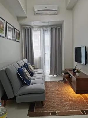 a living room with a couch and a television at Mall of Asia shore 3 residence in Manila