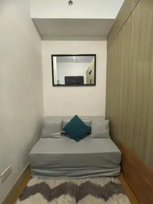 a bed in a room with a mirror on the wall at Grace Residences Condo 1 BR Poolview near McKinley BGC in Manila