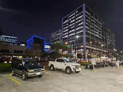 a parking lot with two trucks parked in front of a building at Haven of Tranquility Suite - SMDC Shore 3 (MOA) in Manila