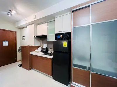 a kitchen with a black refrigerator and wooden cabinets at 1BR Condotel Suite at Sunshine100 City Plaza #SS04 in Manila