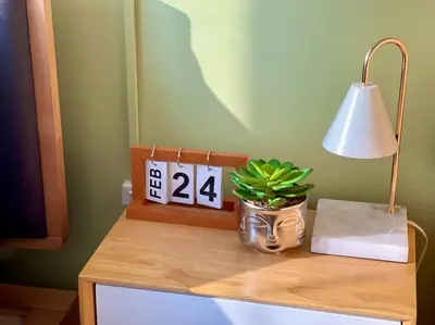 a table with a clock and a lamp and a plant at Elegant 1 BR Condo with Balcony in Uptown Parksuites II, BGC in Manila