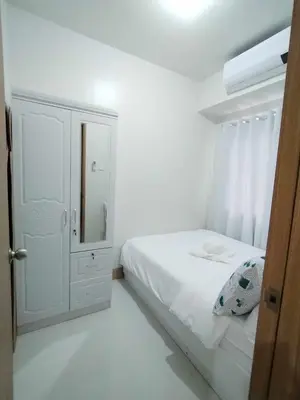 a white bedroom with a bed and a mirror at Cozy 642 shore3 residence tower2 near MOA in Manila