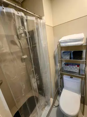 a bathroom with a shower and a white toilet at Comfy unit at SMDC Breeze Residences near PICC, MOA, NAIA Airport, CCP with a view! in Manila