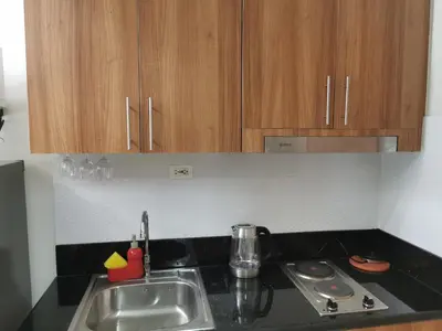 a kitchen with a sink and a stove and wooden cabinets at Moa shore 3 staycation in Manila