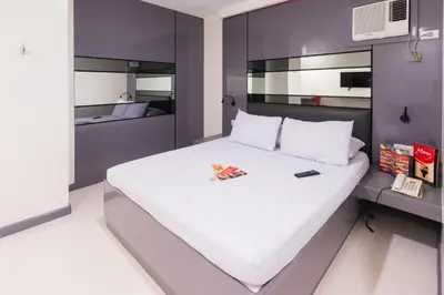 a large white bed in a room with purple walls at Hotel Sogo Guadalupe in Manila