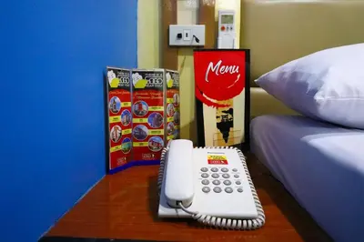 a phone sitting on a table next to a bed at Hotel Sogo Makati Avenue in Manila