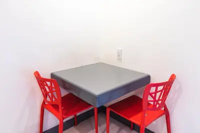 a table with two red chairs sitting next to it at Hotel Sogo Cainta in Manila