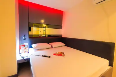 a bedroom with a white bed with a red wall at Hotel Sogo Alabang Rotonda in Manila