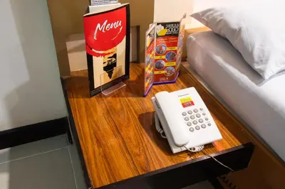 a telephone on a table next to a bed at Hotel Sogo Santolan in Manila