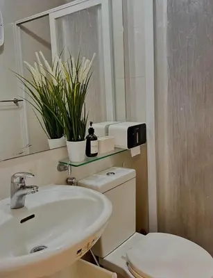 a bathroom with a sink and a toilet and a mirror at Caroshiro Staycation Azure Uban Resort in Manila