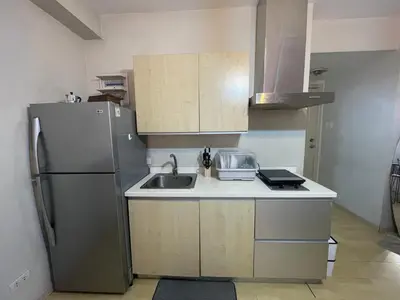 a kitchen with a sink and a refrigerator at SOHO Central EDSA Shaw Condo Pool front with SMART TV in Manila
