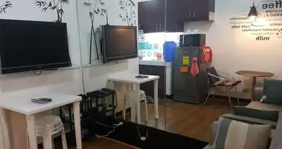a living room with a tv and a kitchen with tables at Rsquared Condo in Manila