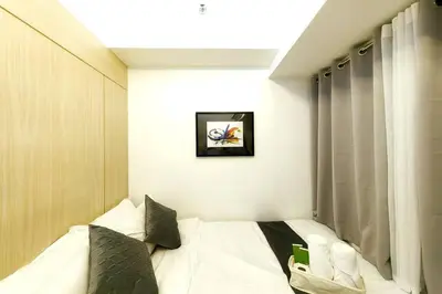 a bedroom with a white bed with a window at 1BR Condotel with Balcony at SM Light Residences #LT05 in Manila