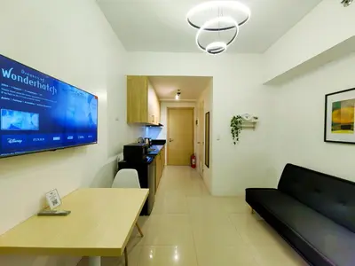 a living room with a table and a tv on the wall at 1BR Condotel with Balcony at SM Light Residences #LT05 in Manila