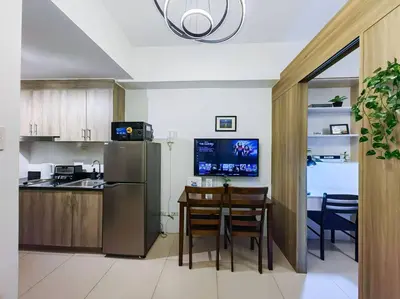 a kitchen with a table and a refrigerator at 1BR Condotel with Balcony at FAME Residences #FM09 in Manila
