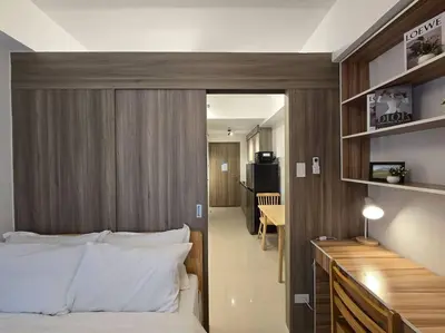 a bedroom with a bed with a wooden headboard at 1BR Condotel with Balcony at FAME Residences #FM14 in Manila
