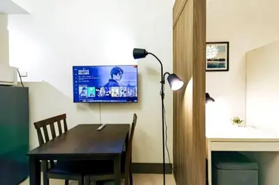 a dining room with a table and a tv on the wall at 1BR Condotel with Balcony at FAME Residences #FM17 in Manila